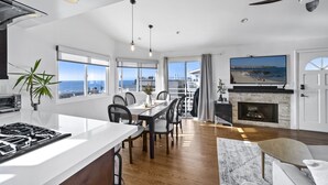 A spacious living area with a large TV, a fireplace, and a dining table. - Top Floor Unit with Panoramic Views Steps to the beach with 3 Parking Spots!  (Manhattan Beach)