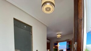 A hallway leading to a bedroom with a bed, a window, and a ceiling light fixture. - Riad Jbara 2 (Rabat)