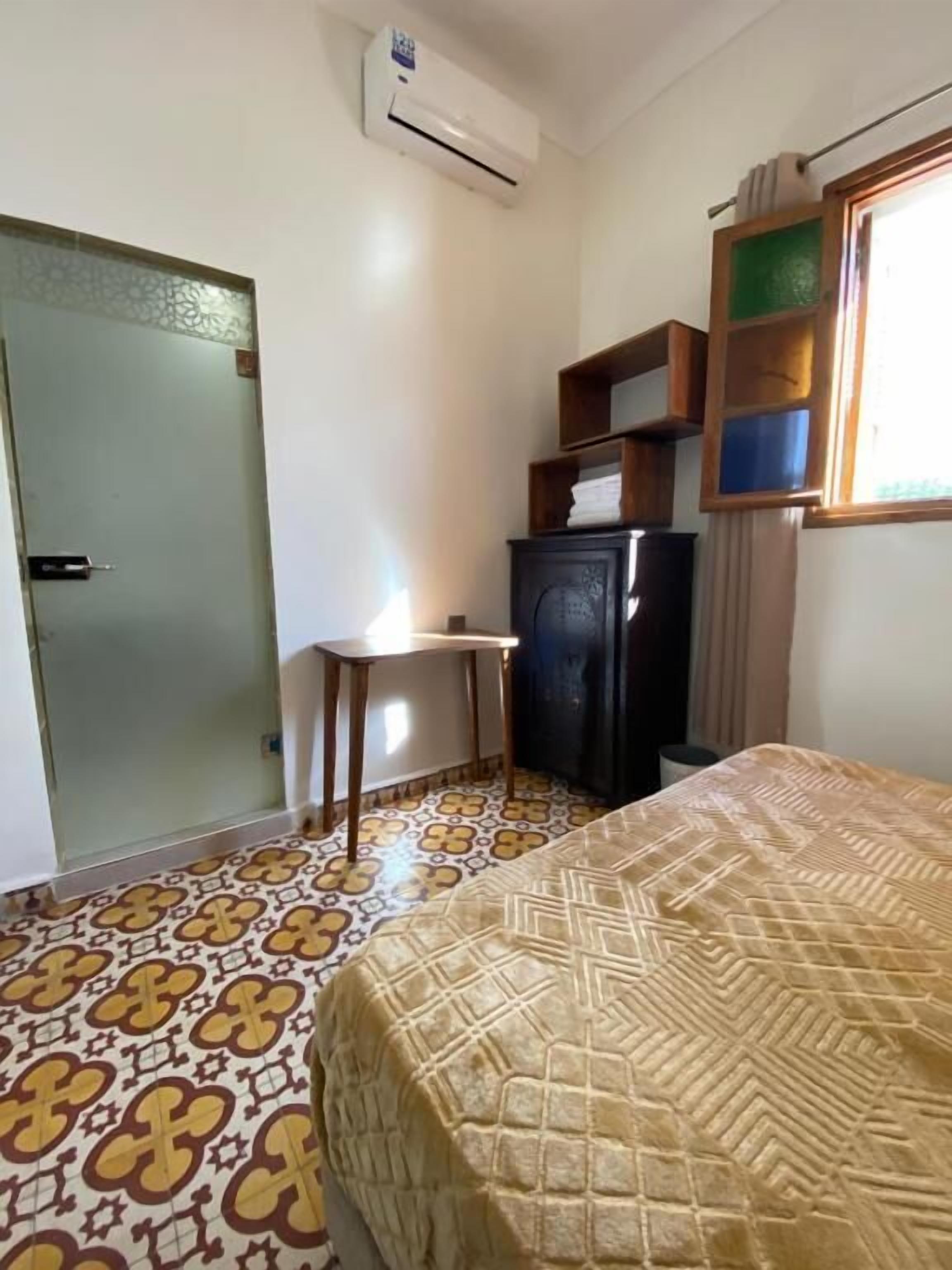 Une chambre comprenant un lit, un bureau, une armoire et un appareil de climatisation.