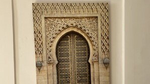 A framed architectural detail with an ornate arch and a patterned door. - Riad Jbara 2 (Rabat)