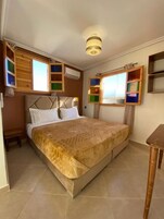 Un dormitorio con una cama grande, un cabecero de madera, un equipo de aire acondicionado y una mesita.