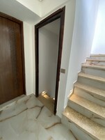 Uma escadaria com degraus de mármore que leva a uma porta com painel decorativo.