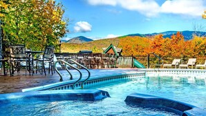 A swimming pool with a view of autumn trees and a mountain in the background.