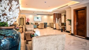 A modern lobby with comfortable seating, a large digital screen, and a decorative vase.