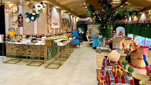 A spacious room with a long counter displaying various items, a large decorative plant, and wicker furniture.