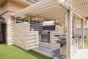An outdoor kitchen area with a grill, sink, and built-in barbecue.