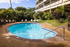 A pool area with lounge chairs and a building in the background.