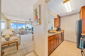 A modern kitchen with wooden cabinets, a granite countertop, and a black refrigerator.