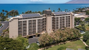 Un hôtel à plusieurs étages, doté d’une tour centrale, de panneaux solaires sur le toit et offrant une vue sur l’océan.