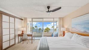 Une chambre d’hôtel équipée d’un lit, d’un bureau, d’une chaise et d’un balcon avec vue sur l’océan.