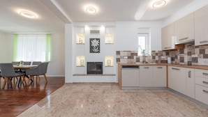 A modern kitchen with a central island, built-in appliances, and a dining area with a table and chairs. - Lovely home in Debelo Brdo with sauna (Debelo Brdo)