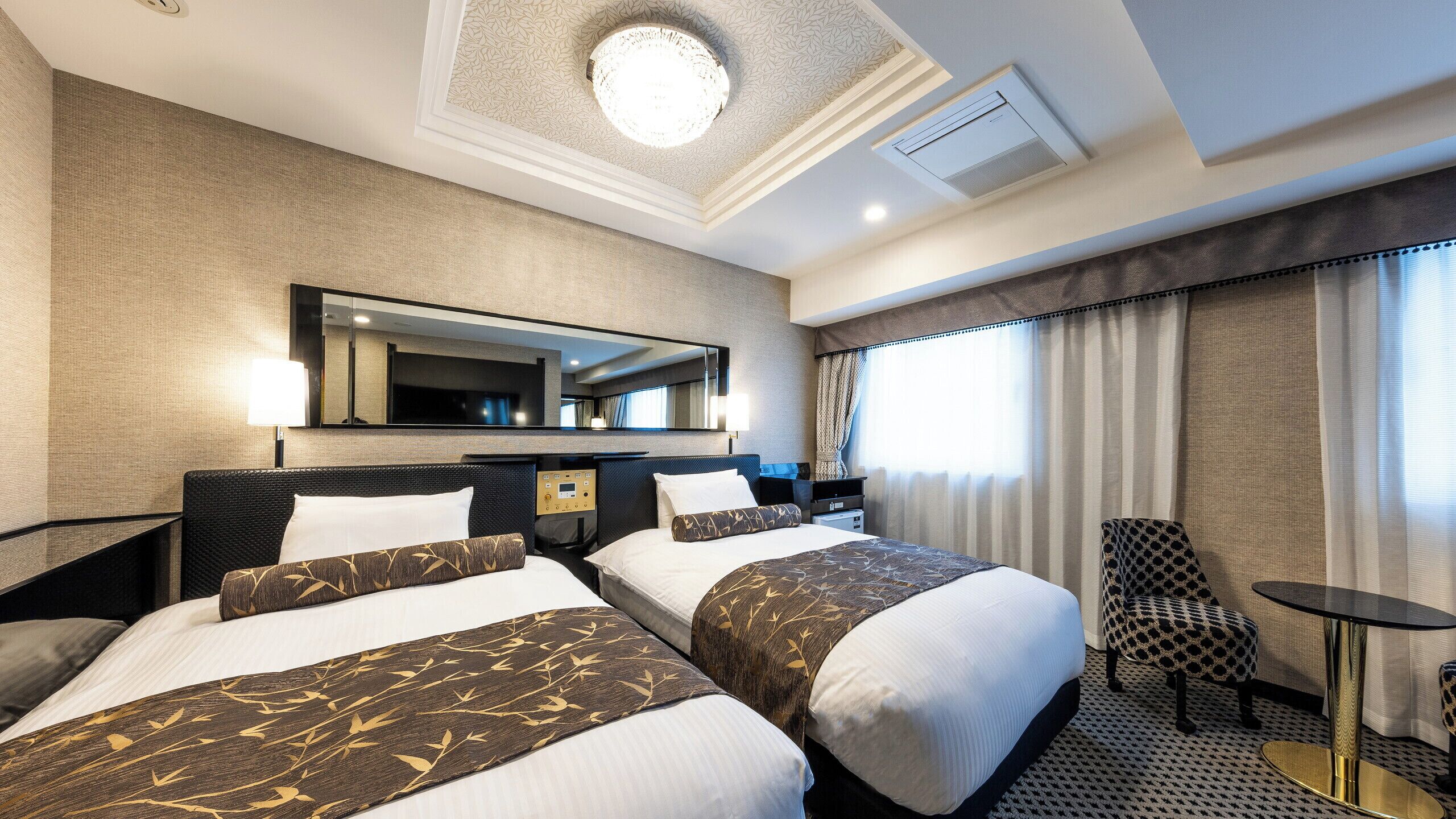 Une chambre d’hôtel avec deux lits, un bureau, une chaise, une télévision et une grande fenêtre avec des rideaux.