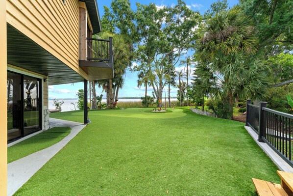 A house with a covered patio, a lawn, and a view of the water.