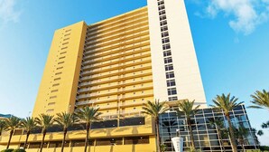Een hotel met meerdere verdiepingen, een gele gevel en een witte toren.