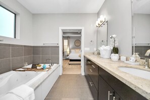 Un bagno moderno con una vasca, uno specchio grande e un mobile lavabo.