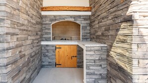 Baño con paredes de piedra, una puerta de madera y un banco.