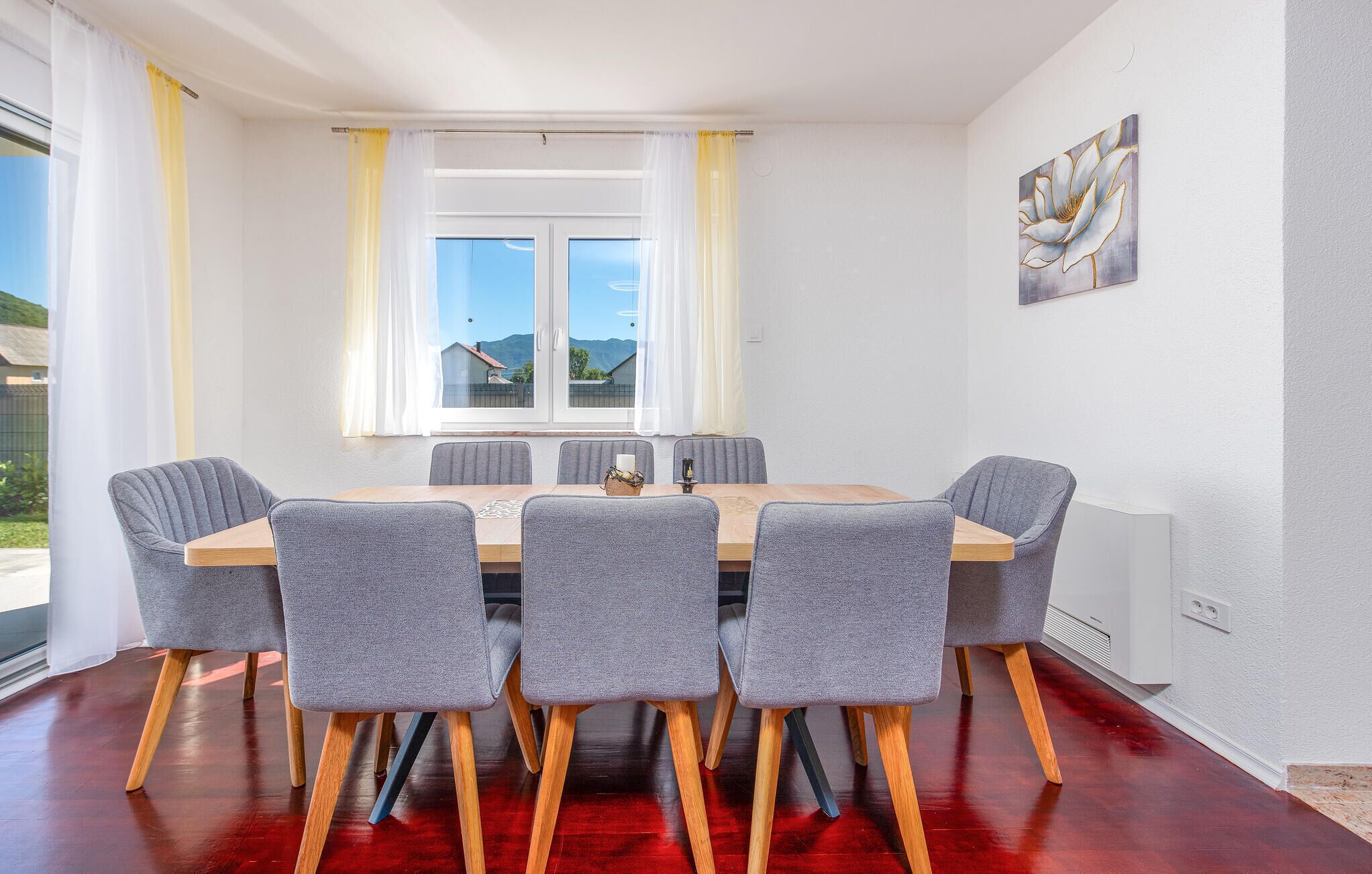 Un coin repas avec une table en bois et six chaises grises aux pieds en bois.
