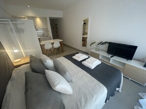 A modern hotel room with a large bed, a desk, and a TV.