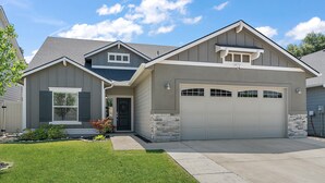 Ein modernes, zweistöckiges Haus mit Garage, einem gepflegten Rasen und einer Wand mit Steinverkleidung.