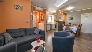 A living room with a grey sofa, a small table with a vase, and a dining area with a table set for two. - Stunning home in Sveti Kriz (Sveti Kriz)