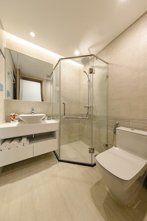 Un baño moderno con ducha acristalada, lavabo blanco y retrete.