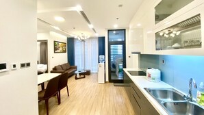 Moderni hotellihuone, jossa on ruokailutila, pieni keittiö ja suuri ikkuna.