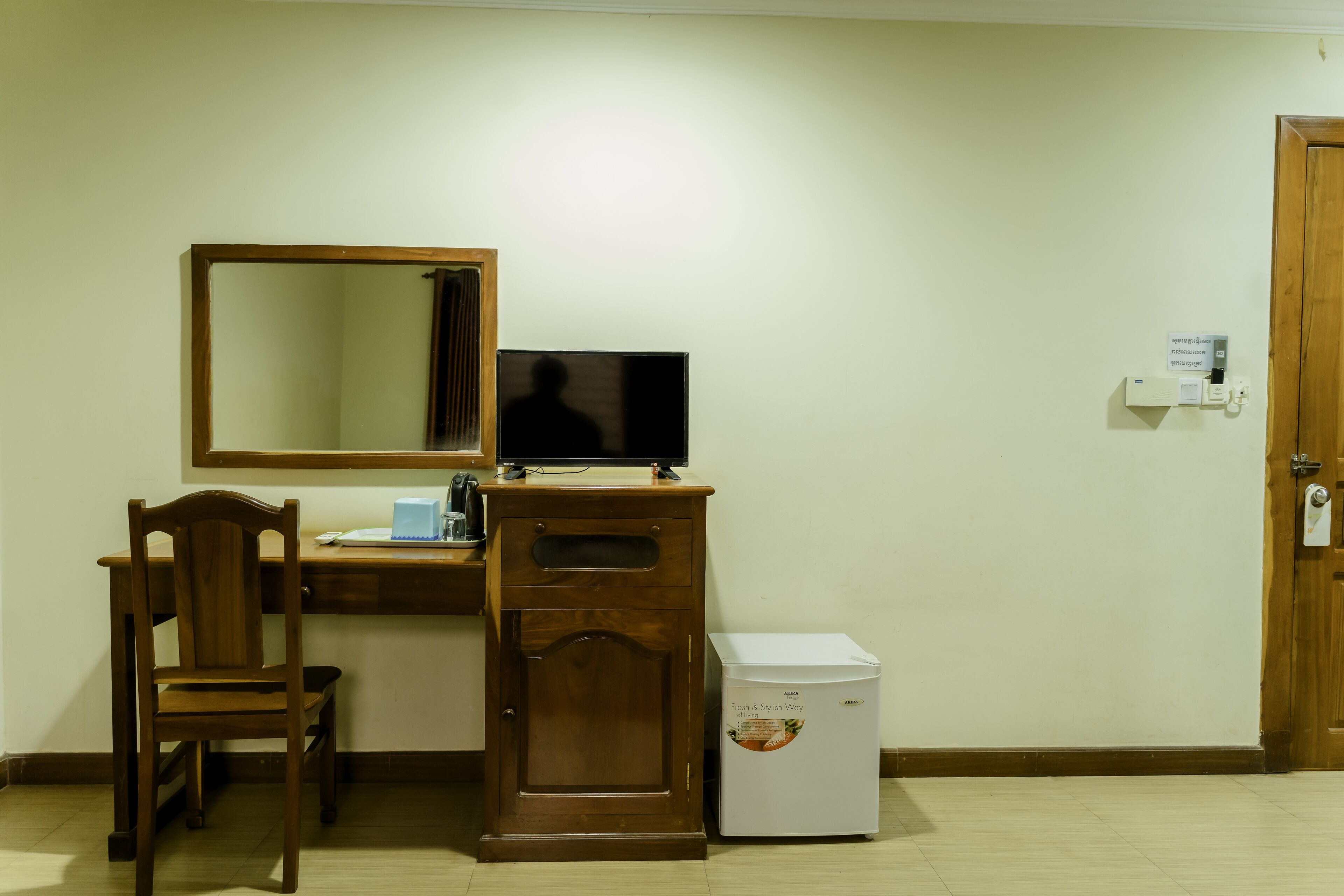 A small room with a wooden desk, a chair, a television, and a refrigerator.