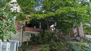 Overlooking a lush garden, this home features a brick facade and a welcoming entrance with a small porch.