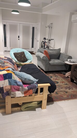 Relax in this stylish living room with a comfortable bed, sofa, and projector for entertainment.
