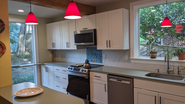 Enjoy cooking in this kitchen with a large window offering a view of the backyard and potted plants.