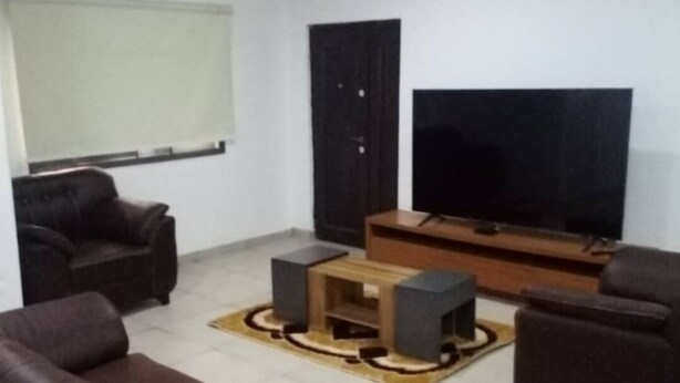 Een woonkamer met een grote flatscreen televisie, donkerbruine banken en een houten salontafel.