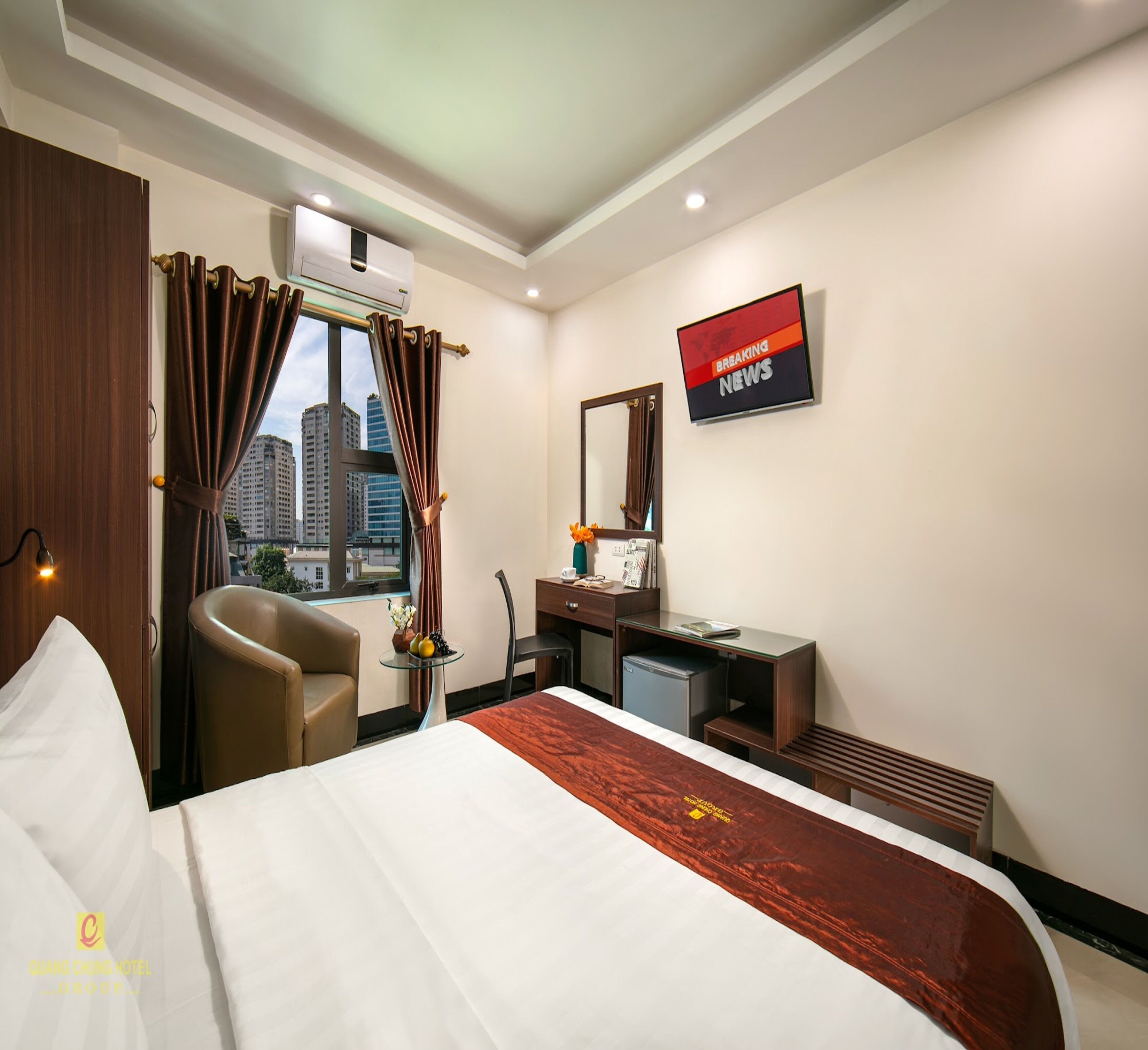 A hotel room with a bed, a desk, a chair, a TV, and a window with curtains.