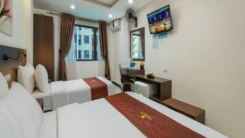 Una habitación de hotel con dos camas, un escritorio, una silla, un televisor y una ventana con cortinas.
