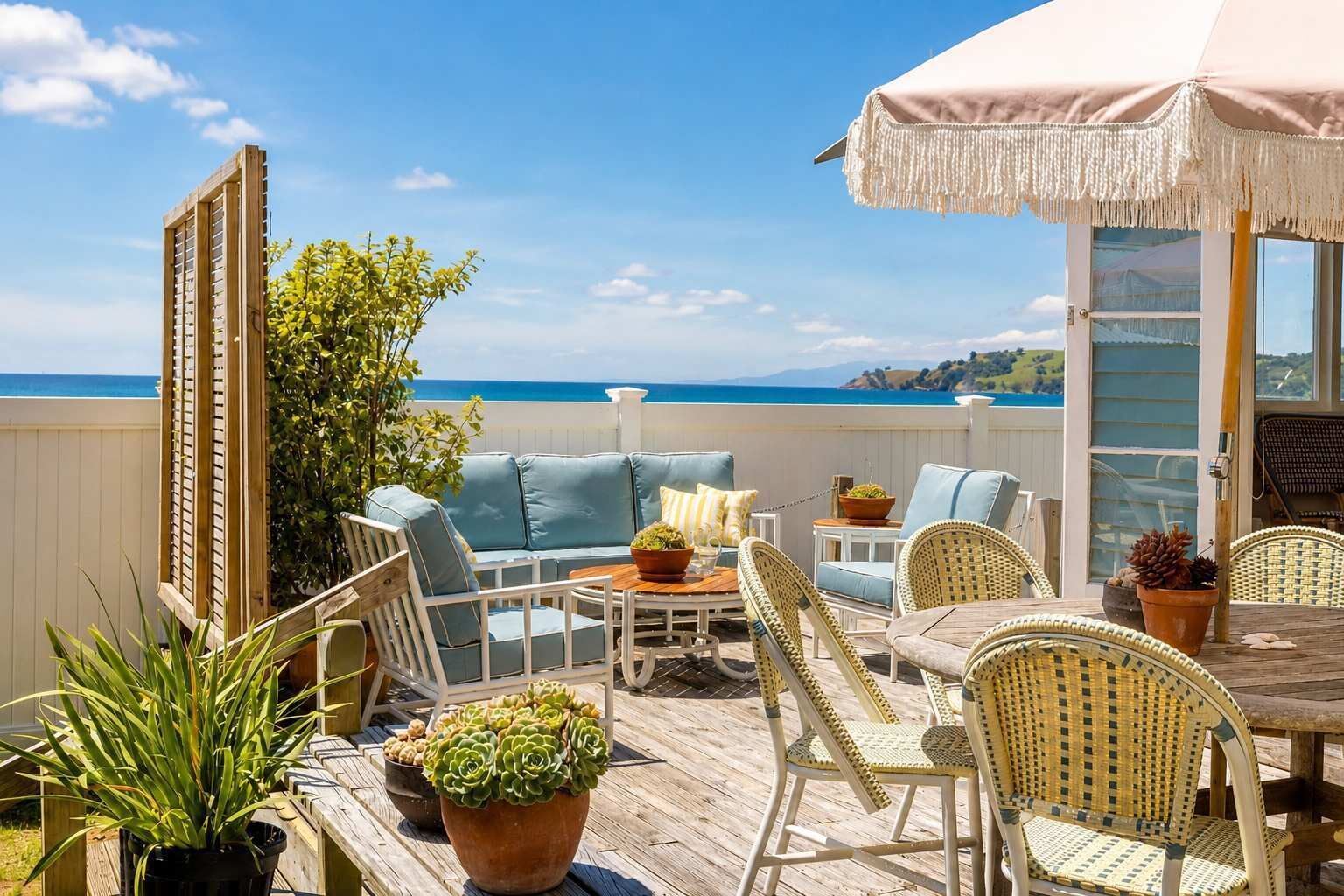 Eine Terrasse mit Gartenmöbeln, einem Tisch und Topfpflanzen.