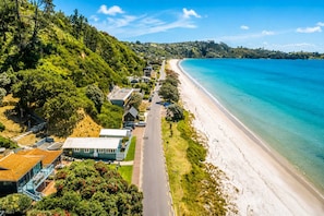 A coastal road with beach access, houses, and greenery.