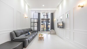A modern living room with a grey sofa, a small wooden table, and a TV mounted on the wall. - Gangneung Dangdangi Dog Pension Blue (Gangneung)