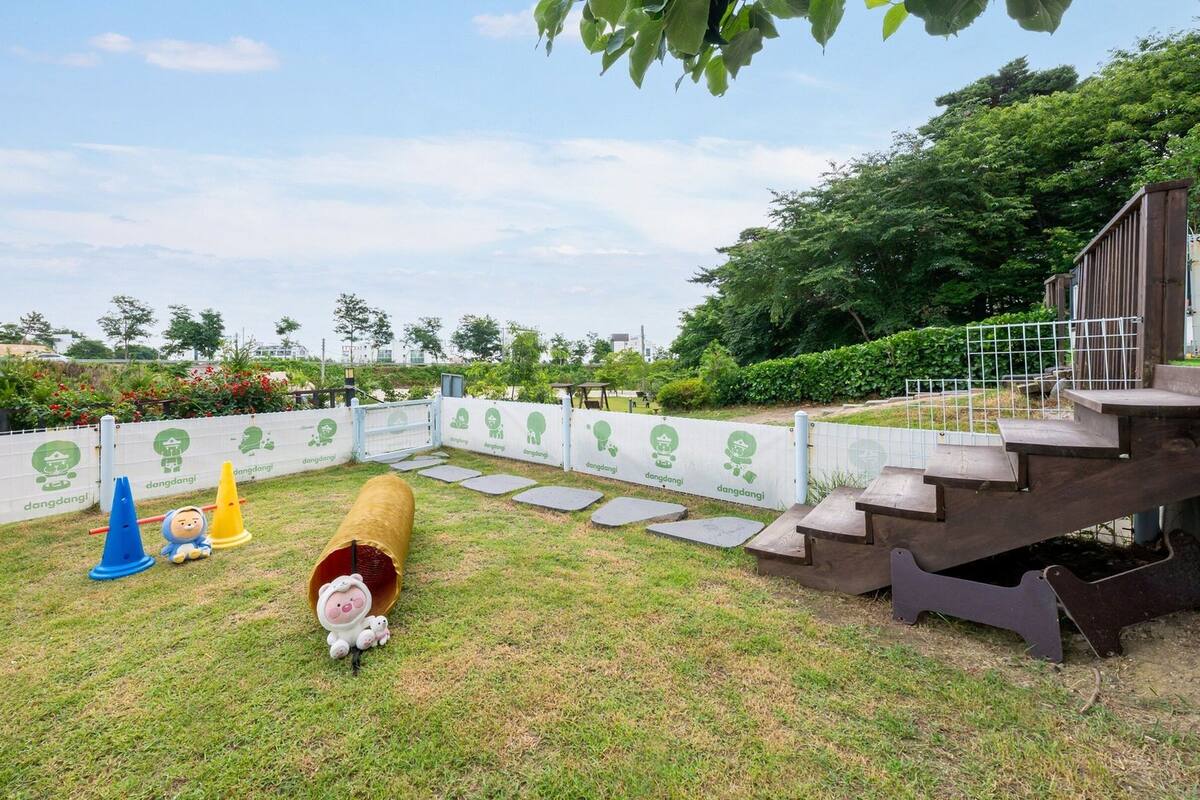 A fenced outdoor area with stepping stones, a wooden bench, and a small slide.