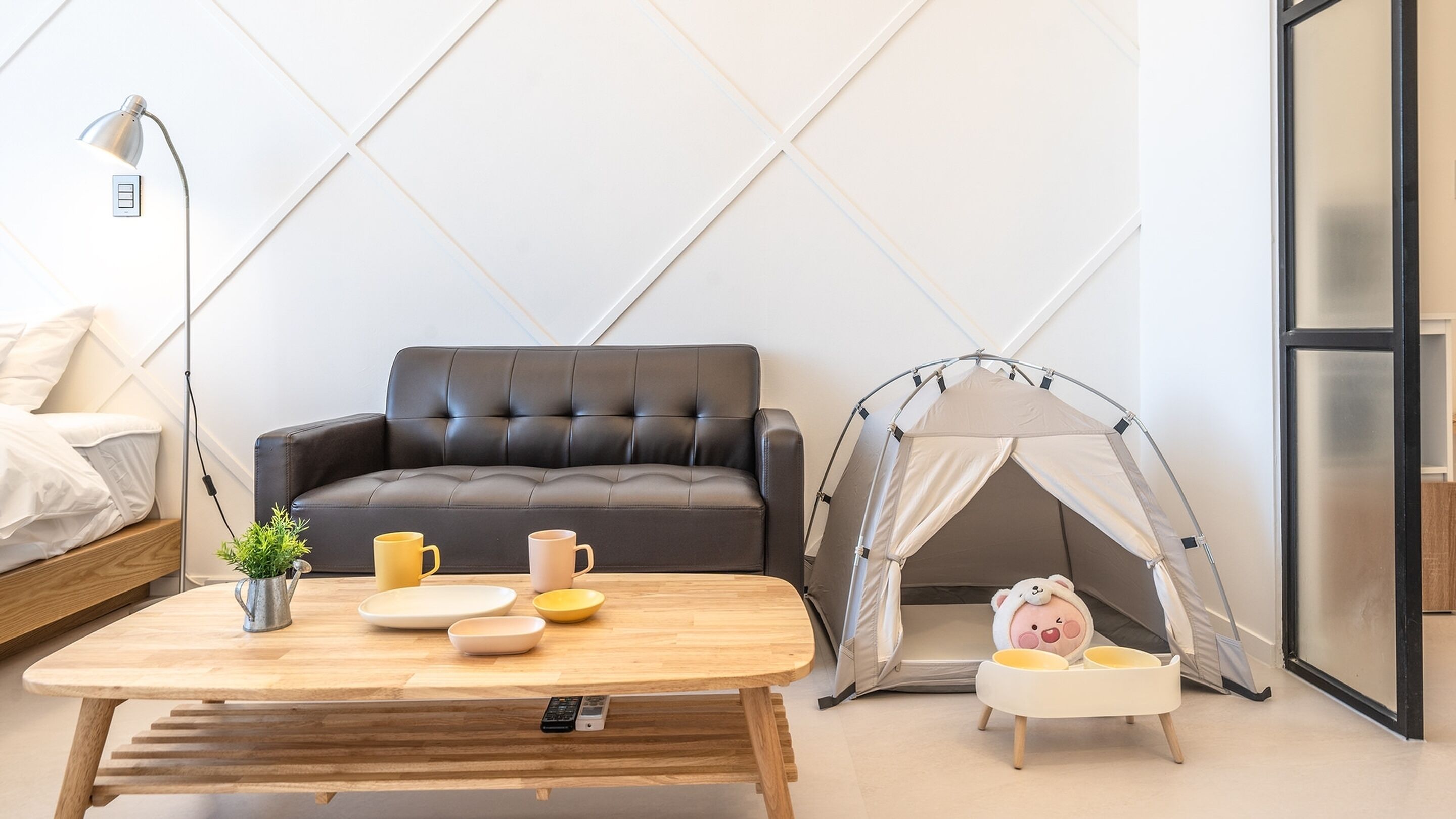 A modern living room with a sofa, a coffee table, a tent, and a pig-shaped bowl.