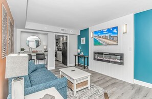 A modern living room with a sofa, coffee table, and a TV mounted on the wall. - Camelot By The Sea 1614 (Myrtle Beach)