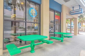 Un restaurant avec une terrasse et un panneau lumineux annonçant un service de livraison de pizzas.