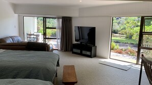 Ein modernes Schlafzimmer mit einem großen Bett, einem Fernseher und einer Schiebetür zu einem Garten.