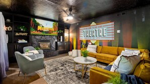A cozy living room with a fireplace, a sofa, a coffee table, and a TV displaying a movie.