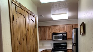 Une cuisine avec des meubles de rangement en bois, un four à micro-ondes, un réfrigérateur et une cuisinière.