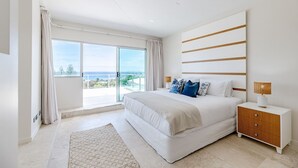 Ein modernes Schlafzimmer mit einem großen Bett, einem Nachttisch und Blick ins Freie.