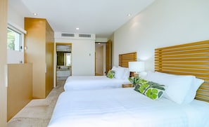 Een hotelkamer met twee bedden, een badkamer en een gang naar een andere kamer.