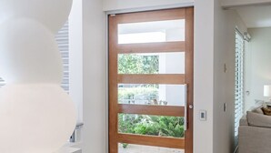Ein modernes Interieur mit Holztür, weißen Wänden und einem beigefarbenen Sofa.
