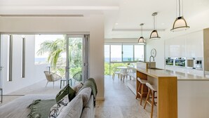 Eine moderne Küche mit einer großen Kochinsel, einem Essbereich mit Blick und einem Wohnbereich mit Sofa und Aussicht.