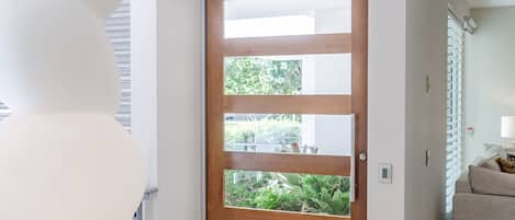 Un interior moderno con una puerta de madera, paredes blancas y suelo de baldosas.