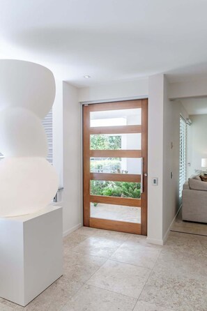 A modern interior with a large white sculpture, a wooden-framed glass door, and a beige sofa. - The Platinum 3BR Luxe Residence in Sunshine Beach (Sunshine Beach)