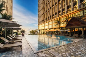 A hotel pool area with lounge chairs and umbrellas, surrounded by tall buildings.